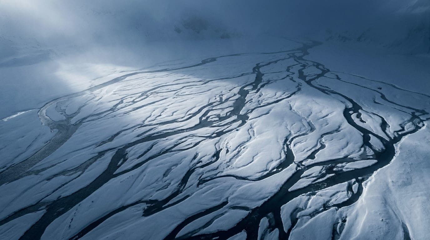 Kühle Alpenlandschaft in Blaustunden-Tönen: unzählige feine Schmelzwasserrinnen, die dicht ein helles Schneefeld durchziehen.